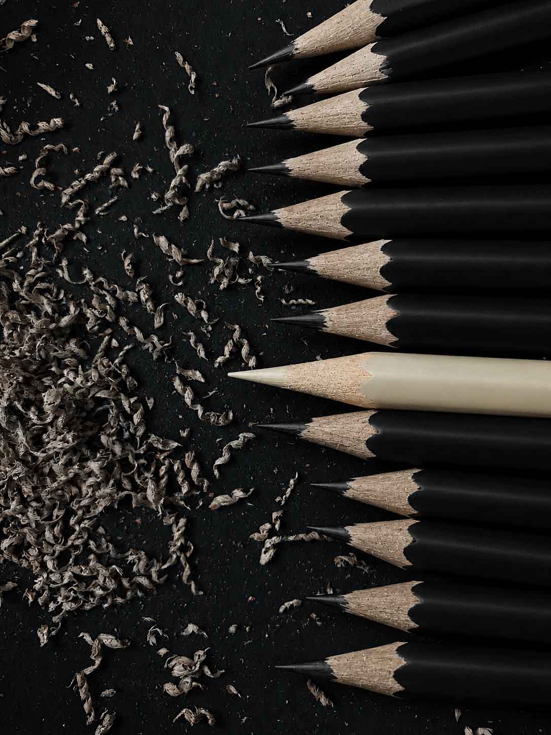 Crayon clair parmi des crayons noirs, illustration de la singularité de marque accompagnée par Bruit Pur Design
